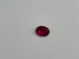 a red oval shaped ruby stone on a white surface