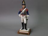 figurine of a man in a uniform with a sword on a wooden base