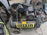 un petit compresseur d'air posé par terre à côté d'un tracteur