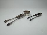 two silver spoons and a silver cup on a white surface