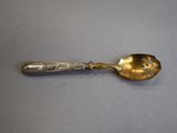 an antique silver spoon on a table with a silver handle