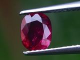 un gros plan d'un diamant rouge tenu par une pince