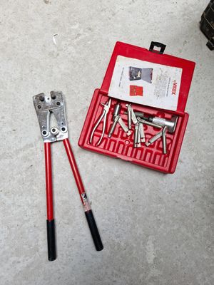 une boîte à outils rouge contenant des outils et une paire de pinces, posée par terre