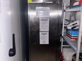 a stainless steel refrigerator in a narrow room with shelves