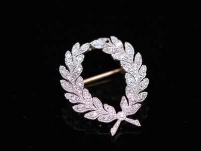 a close up of a brooch with a leaf design on it