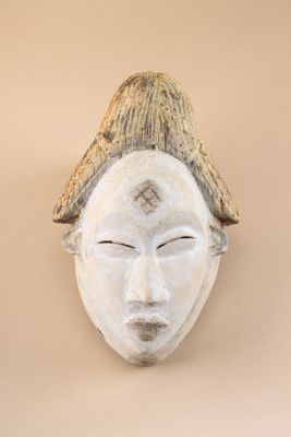 a white mask on the wall with a hat on it