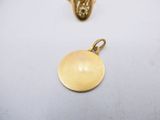 a close up of two gold pendants on a white surface