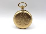 a close up of a gold pocket watch on a white surface