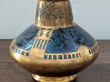 a blue and gold vase sitting on a wooden table