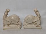 paire de figurines en céramique blanche représentant un homme et une femme assis sur une tortue