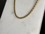 a close up of a gold chain on a marble block