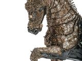 statue of a horse with spikes on it ' s head sitting on its hind legs