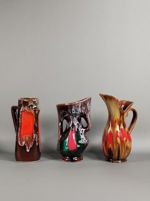 quatre vases de couleurs différentes sont alignés sur une surface grise