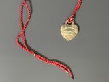 a close up of a red rope with a heart shaped tag on it