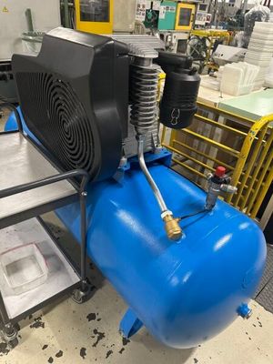 un compresseur d'air posé sur un réservoir bleu dans une usine