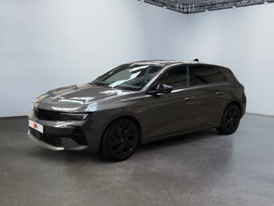 La voiture grise est garée dans une grande pièce aux murs blancs.