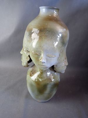 a small vase with a face on it sitting on a table