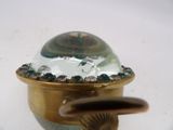 a small glass object with a gold base and some green beads