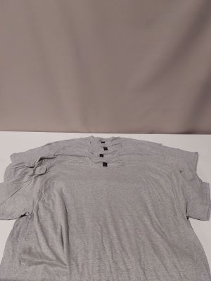 a grey shirt sitting on top of a white table next to a pair of scissors