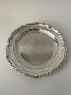 assiette en argent plaqué avec un bord festonné sur un fond blanc