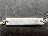 a close up of a silver plate on a chain on a black surface