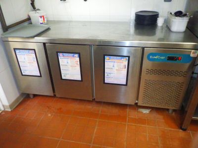 trois réfrigérateurs en acier inoxydable dans une cuisine au sol carrelé de couleur orange