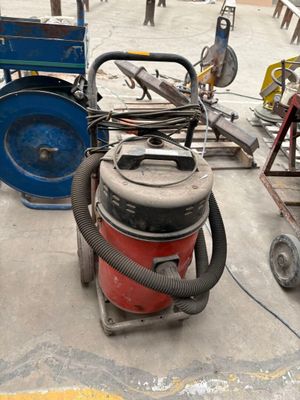 a red and blue vacuum sitting on the floor next to a blue cart