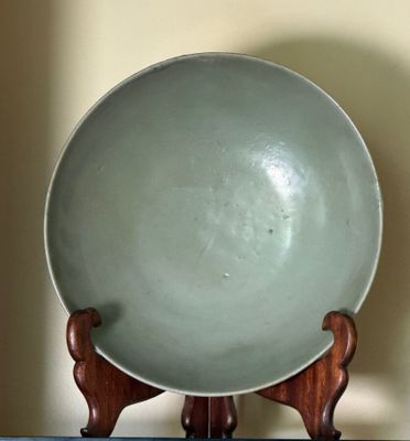 a green bowl sitting on top of a wooden stand