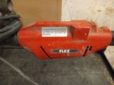 a close up of a red electric drill on the ground