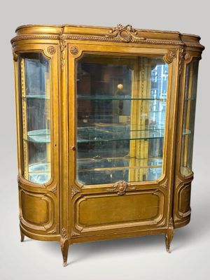 une vitrine ancienne avec des portes vitrées et des garnitures dorées