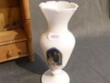 a white vase with a picture on it next to a wooden cabinet
