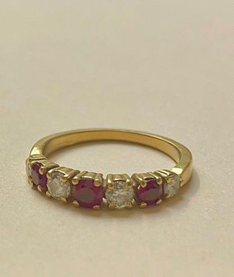 un gros plan sur une bague en or jaune sertie de pierres roses et blanches