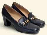 un gros plan sur une paire de chaussures noires posées sur une surface blanche