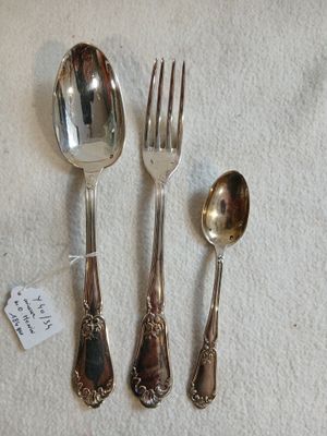 trois cuillères en argent et deux cuillères en argent posées sur une nappe blanche