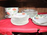 many plates and bowls on a red cloth on a shelf