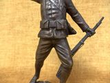 statue en bronze représentant un soldat tenant un fusil et pointant vers quelque chose
