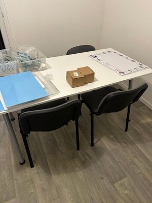 une table blanche avec deux chaises noires et une boîte marron posée dessus