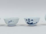 three blue and white porcelain bowls and a vase on a white surface