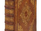un vieux livre relié en cuir, orné de motifs élaborés sur la couverture et les tranches