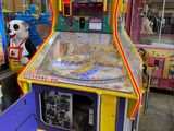 une image représentant un flipper dans une pièce où se trouvent d'autres jeux