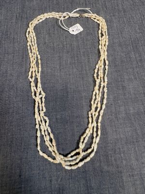 un collier composé de trois rangs de perles de verre sur fond gris