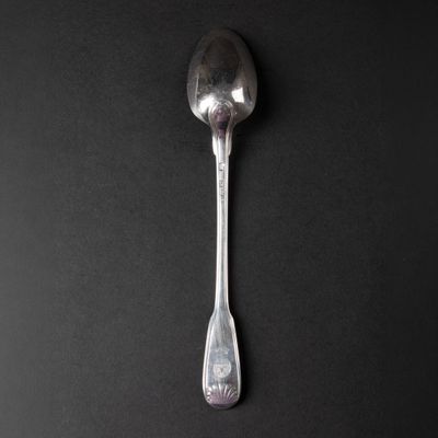 a silver spoon with a spoon handle on a black surface