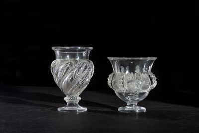two glass vases sitting on a table with a black background