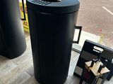 une poubelle noire posée devant une fenêtre