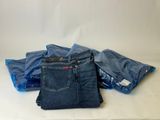 three pairs of blue jeans sitting on top of a white table