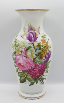 un vase avec des fleurs peintes dessus, posé sur une table