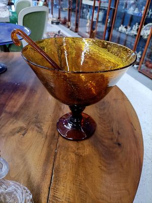 un saladier en verre posé sur une table en bois, avec une cuillère à l'intérieur