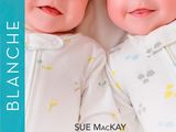 two babies laying next to each other on a bed