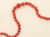 an image of a red beaded necklace on a white surface