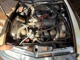 a man standing next to a car with a engine in it